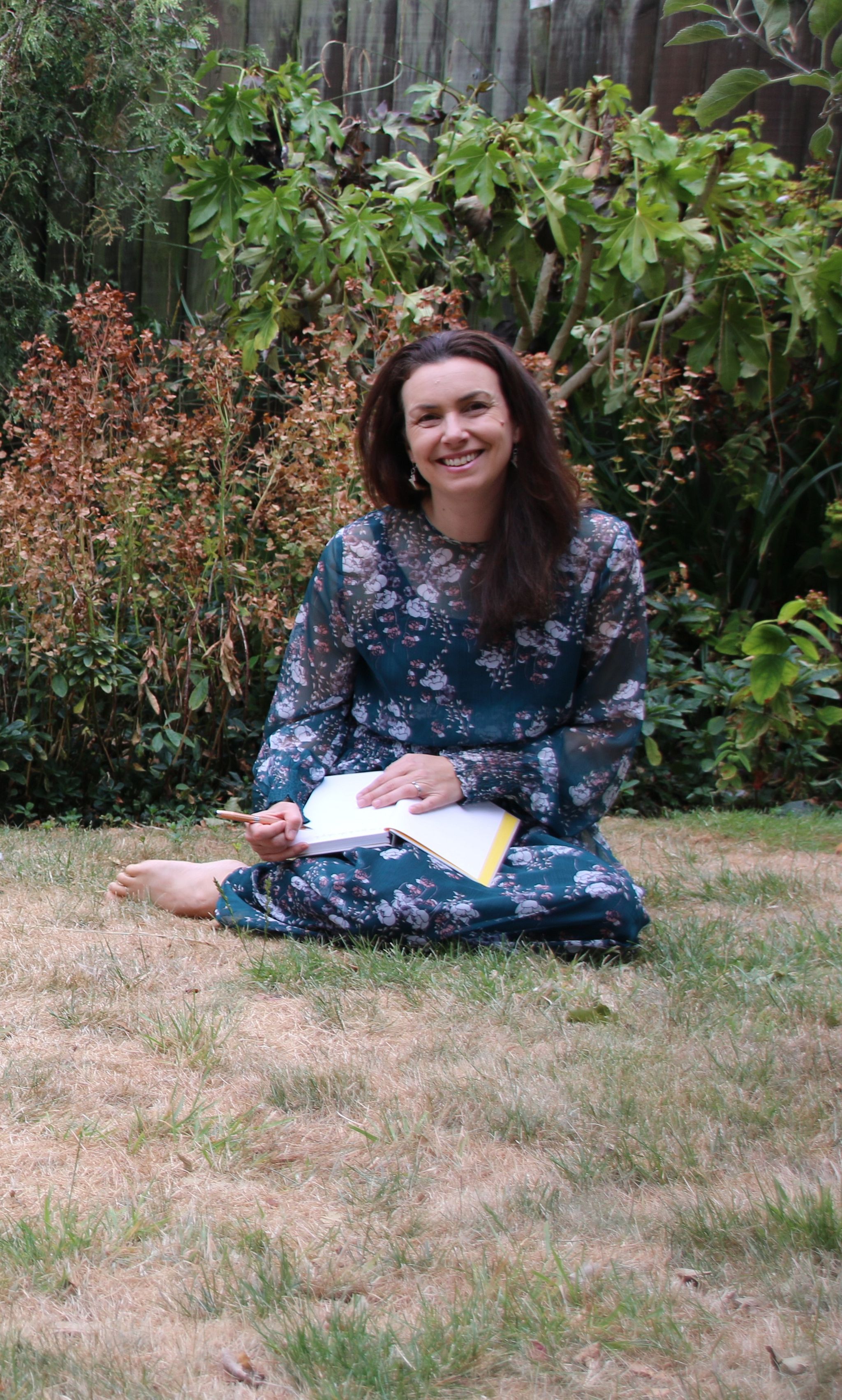 Vikki Marmaras sits on the grass with a notepad on her lap.