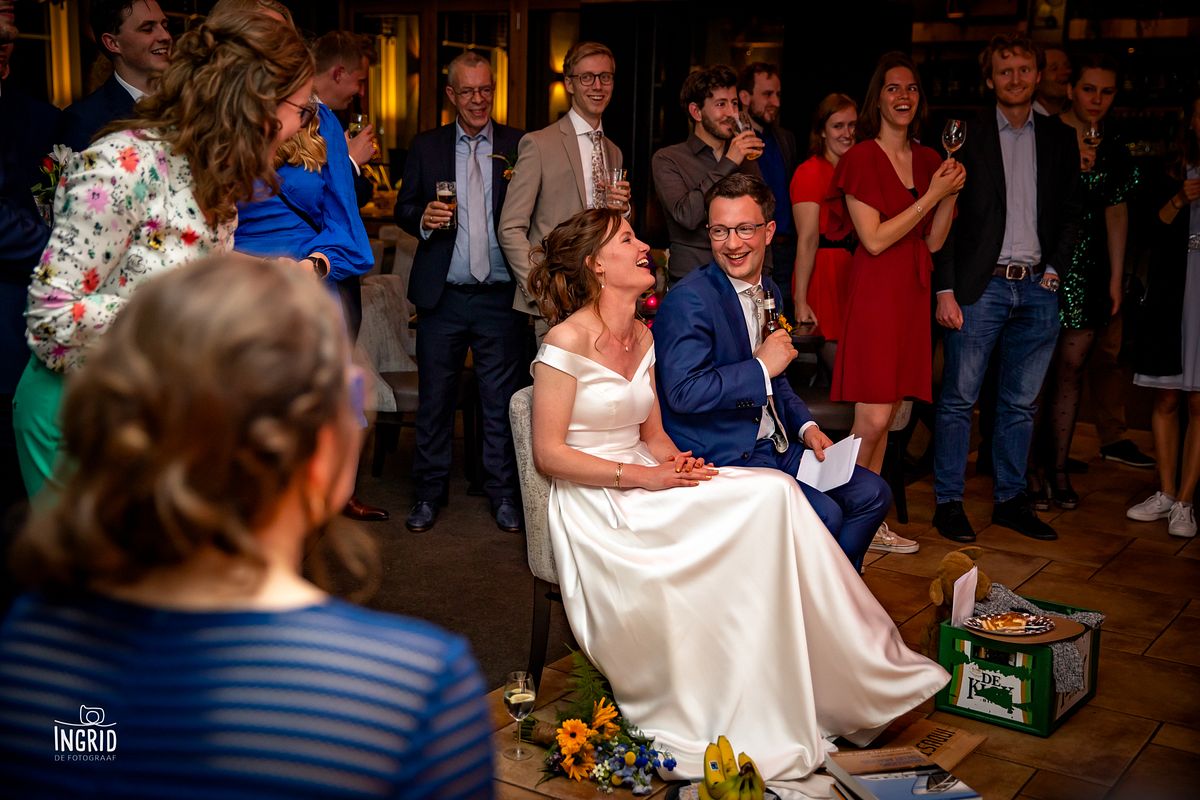 Bruidspaar lacht om de stukjes van de gasten Bruidspaar lacht om de stukjes van de gasten