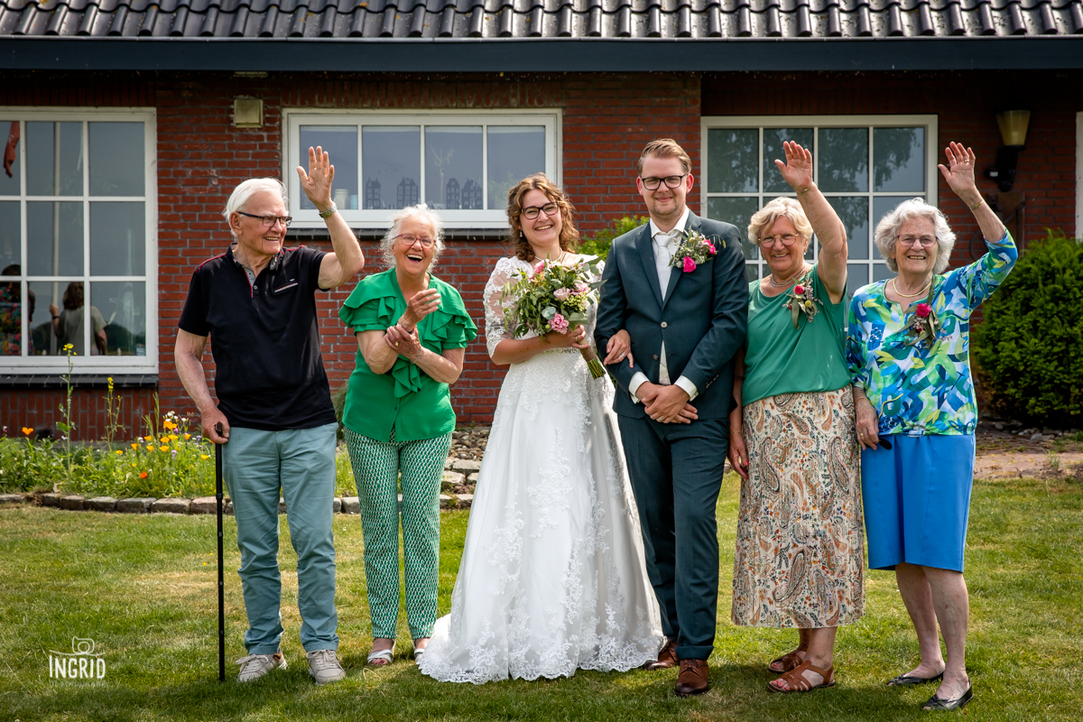 Groepsfoto bruidspaar met opas en omas die juichen