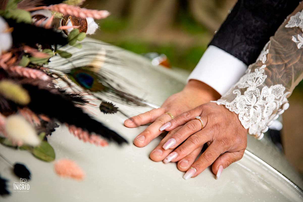 Ringen om de handen van het bruidspaar, met droogbloemenboeket