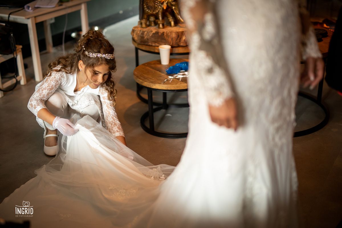 bruidsmeisje legt de sleep van haar moeders trouwjurk recht